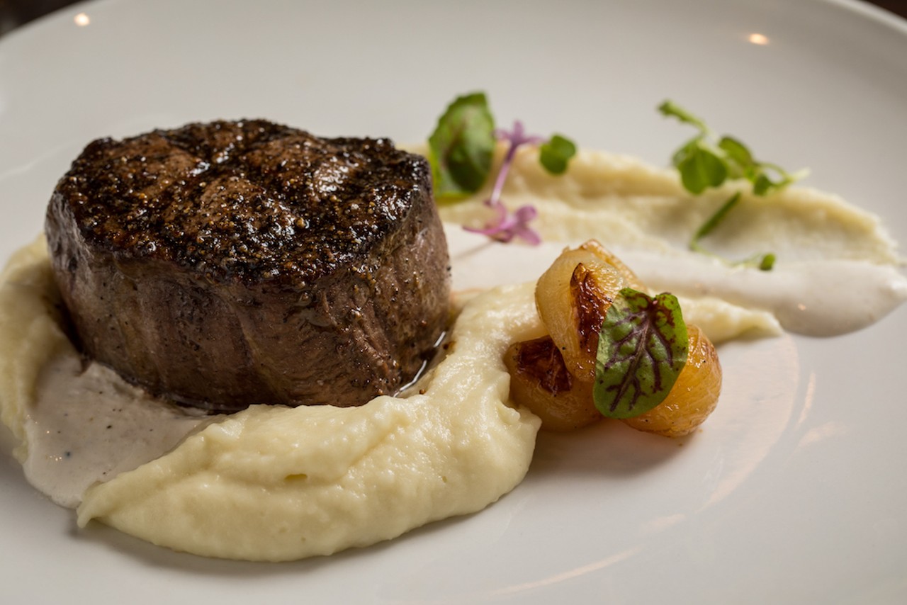 Grilled beef tenderloin is au poivre-crusted and served on top of a smooth potato pur&eacute;e with hints of garlic.