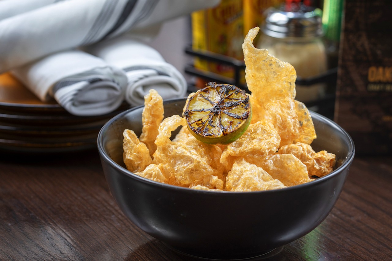 Pork cracklings are light, crisp fried pork rinds with a dash of chili oil and a grilled lime half to add a pop of fresh acidity.