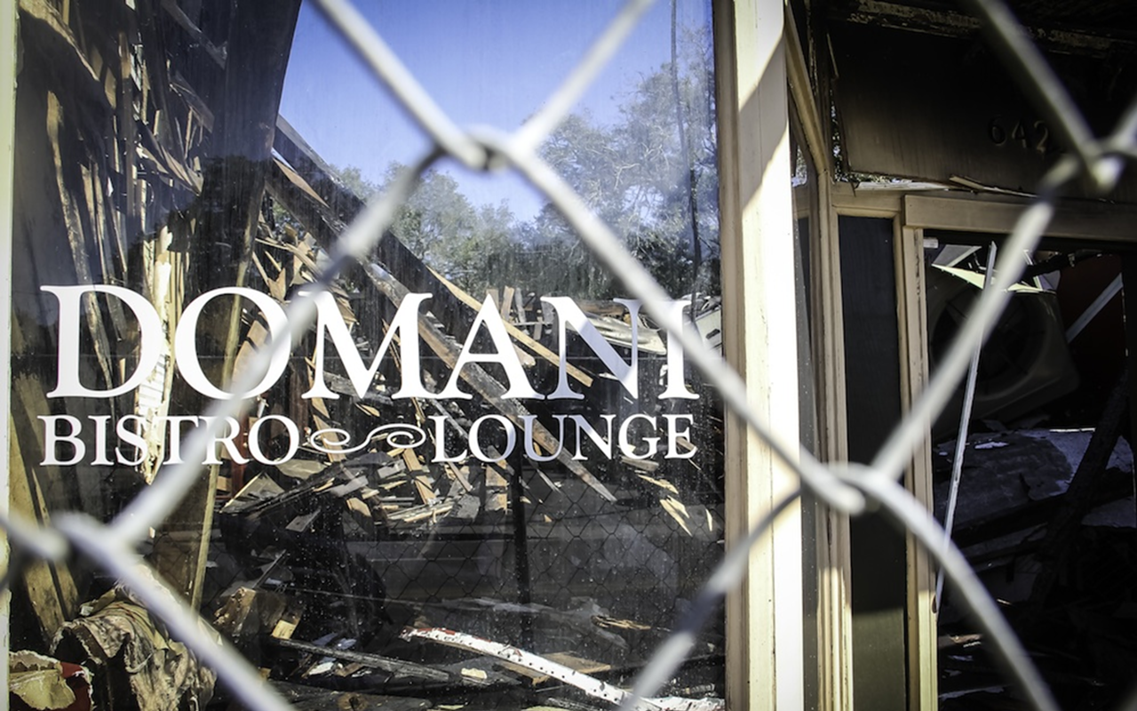 REFLECTIONS OF DEVASTATION: A fire-damaged collapsed roof can be seen through Domani's front window.