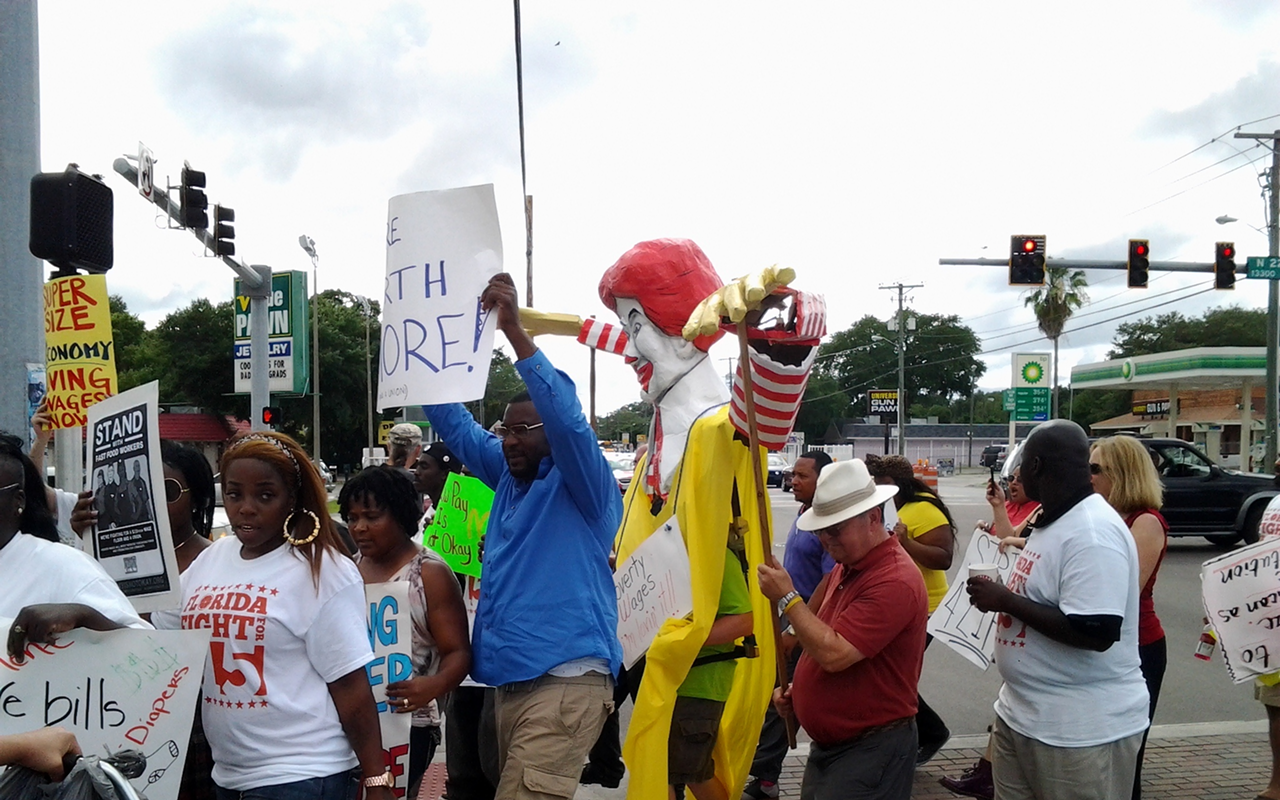 Fast-food workers from Tampa cross an intersection, rallying for increased wages and the right to form a union.