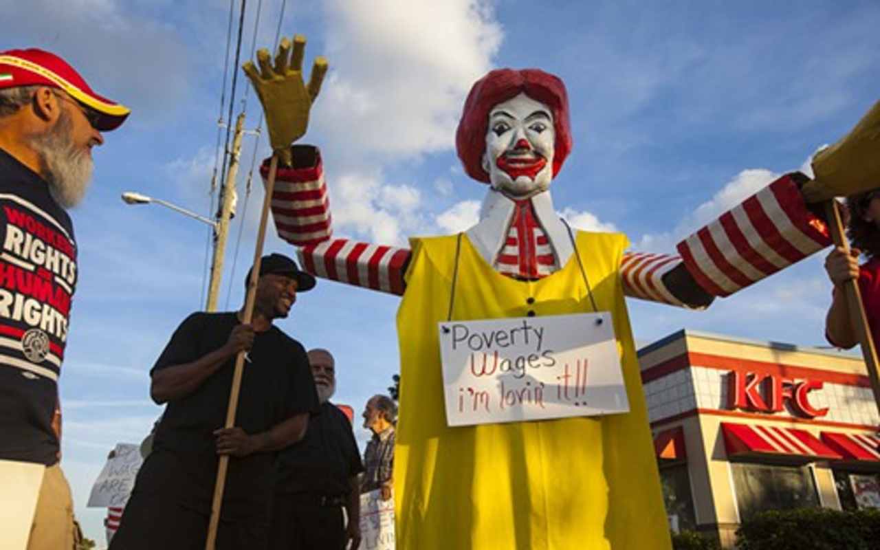 Protesters lead a Ronald McDonald effigy in protest of minimum wage and working conditions.