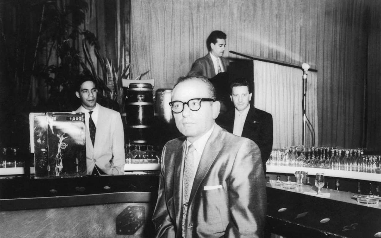 Santo Trafficante Jr. sitting on a stool in front of his bar at the Sans Souci Night Club in Havana, Cuba.