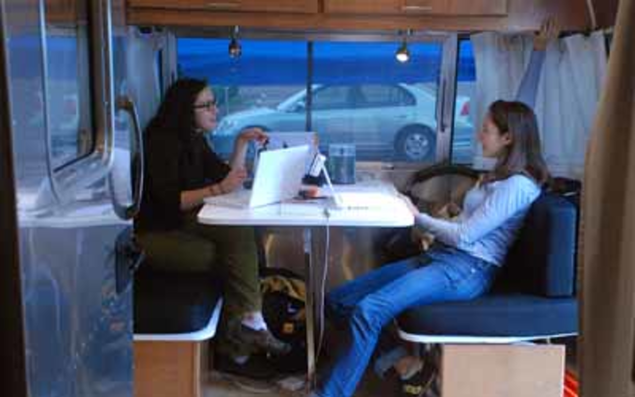 Whitney Henry-Lester and Nina Porzucki work in the StoryCorps Airstream trailer's office space during a recording session.
