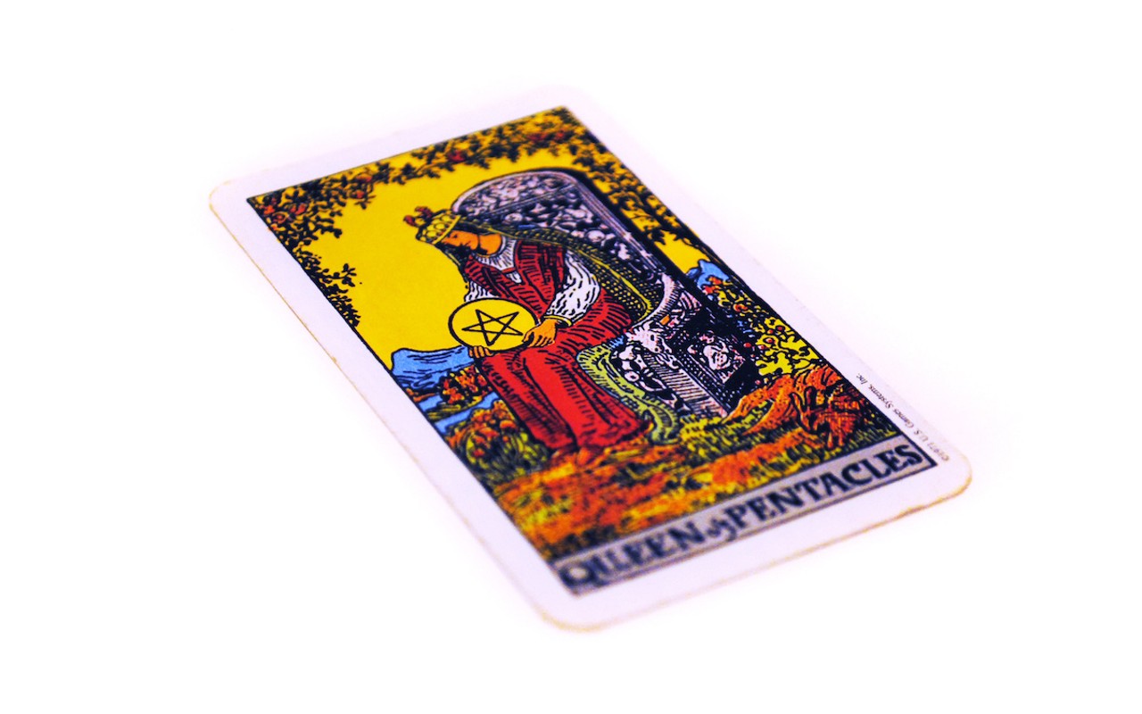 The Queen of Pentacles in my deck is a queen with a crescent horn headdress, holding a flower close to her face as she gazes down, holding her billowing robes.