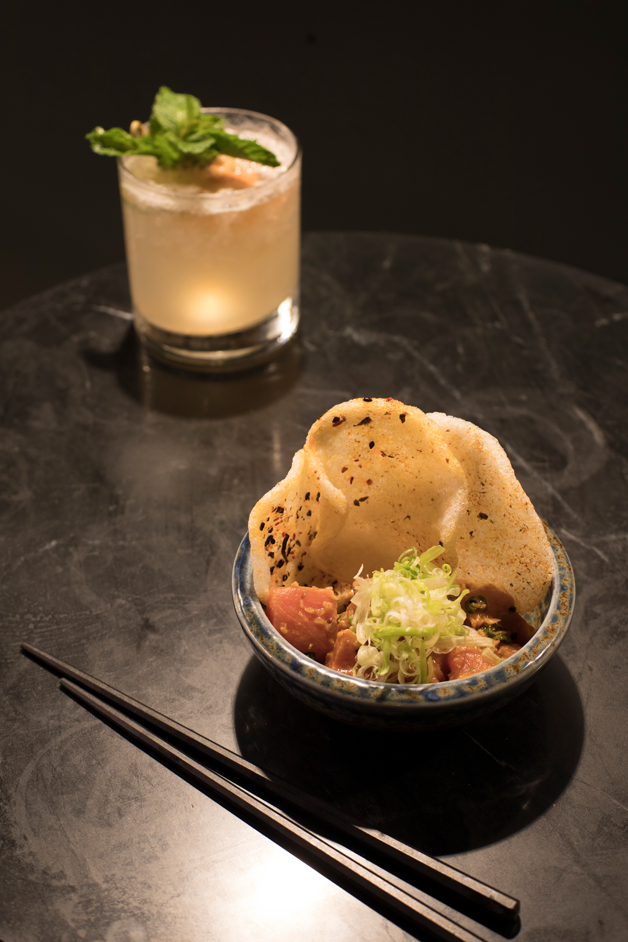 Pictured with another cocktail, Genji Glove, the fresh tuna poke arrives with big, complementary shrimp chips.