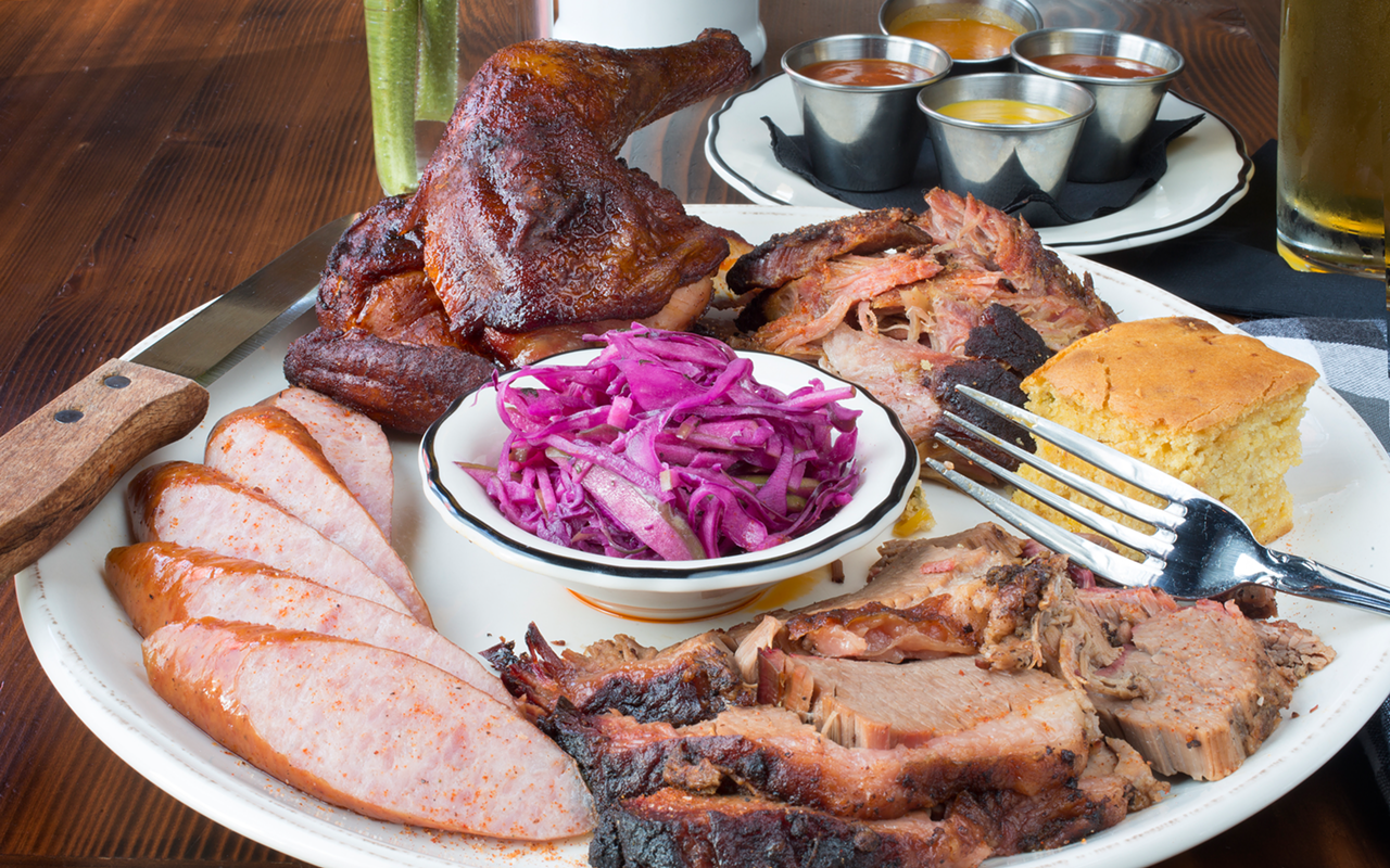 A Proper Sampler — smoked chicken, pulled pork, beef brisket and garlic sausage served with house slaw, barbecue sauces and cornbread.