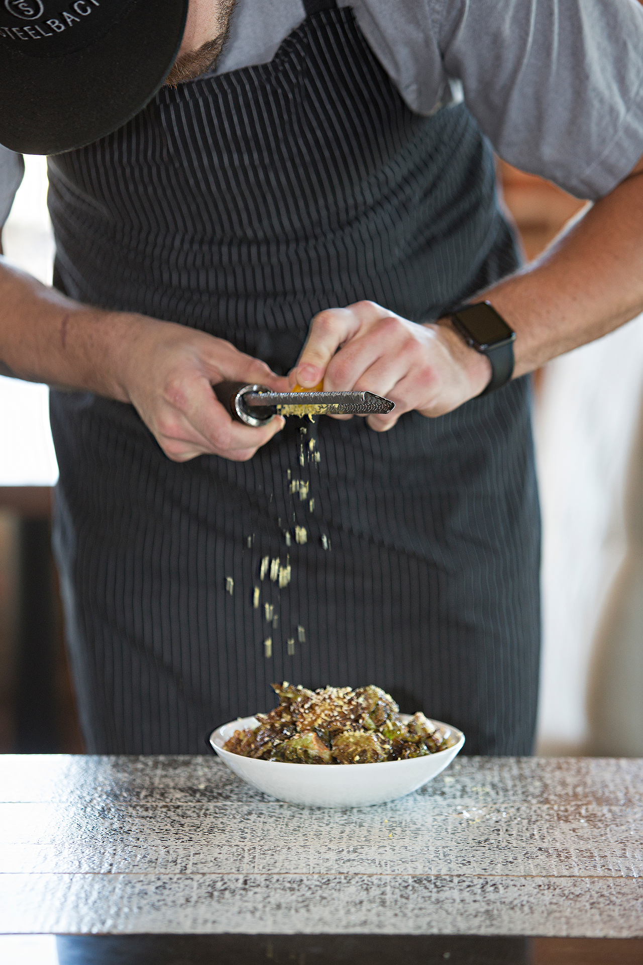 Steelbach chef-partner Nathan Hardin uses a microplane grater on cured egg yolk, adding flavor to Brussels sprouts.