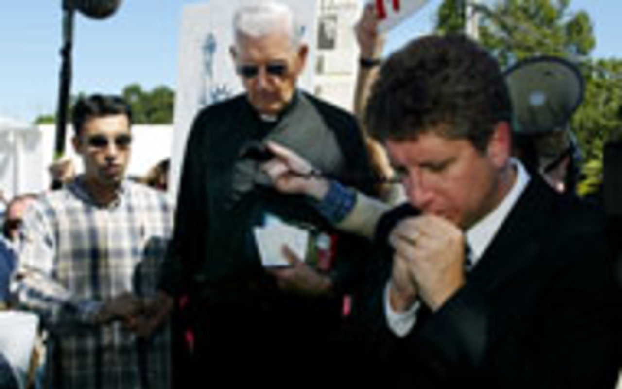PRAYERS AND INTERVENTION: Pro-life activist 
    Randall Terry (right), president of the Society for Truth 
    and Justice, prays with Monsignor Thaddeus G. 
    Malanowski (center) during a protest outside 
    Woodside Hospice, before the governor ordered 
    Terris feeding tube be re-inserted.