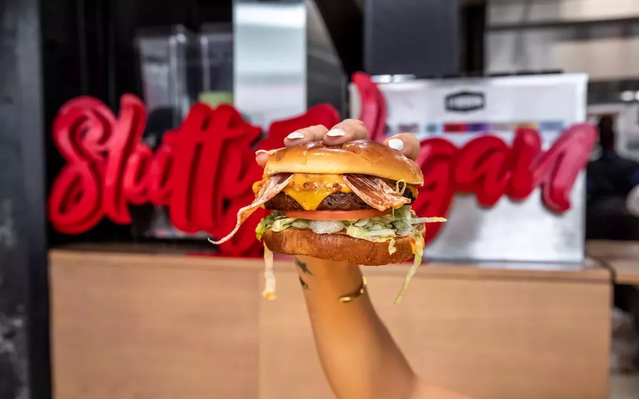 Slutty Vegan's 'One Night Stand' burger with a plant-based patty, Slutty Strips vegan bacon, vegan cheese, LTO, and Slut Sauce on a vegan Hawaiian bun.