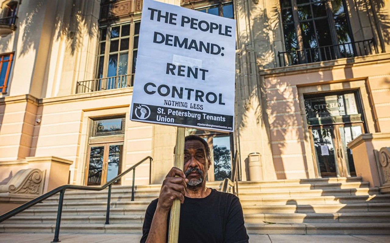 A protester at St. Petersburg City Hall holds a sign demanding rent control.