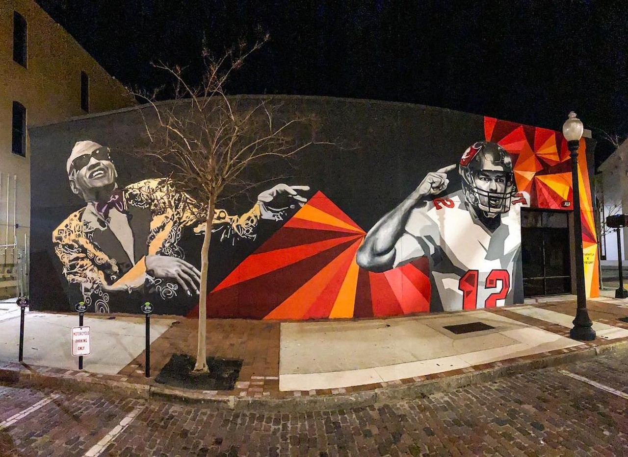 Matt Kress and Audrey Jennifer bring Ray Charles & Tom Brady together in Tampa
1000 N Florida Ave., Tampa
Don’t ask us why Ray Charles and Tom Brady share a wall off Florida Avenue in downtown Tampa, but you’ve got to see it. 
Kress and Jennifer completed the mural in 2021 in advance of Super Bowl LV. The game was historic for several reasons. One, it was the first time a team—our Buccaneers—got to play a Super Bowl game in its home stadium. Second, due to COVID, it was the least-attended Super Bowl in history, with attendance limited to 25,000 fans. Third, Tom Brady became the oldest quarterback in NFL history to win a Super Bowl at age 43. And fourth, it marked the second Buccaneers Super Bowl victory in history. 
The first time I saw the mural, I thought perhaps the artists added Tom Brady later, but Kress and Jennifer deliberately painted the two together. In a 2021 Interview with 10 Tampa Bay, Jennifer said, “Tom Brady is a new addition to our area, but he's somebody certainly to be celebrated and the whole Bucs team making history this weekend. Ray Charles being somebody who is a classic, I think everybody looks up to. I just think people will find unity in it with the sports and music. Those are things that bring everybody together.”
So you can ask us why Ray Charles and Tom Brady are on the same mural. Both lived in Tampa at different times, but to artists Kress and Jennifer, they’re symbols of how sports and music bring people together in Tampa. Go Bucs! Hey, hey!Photo via Audrey Jennifer/Facebook