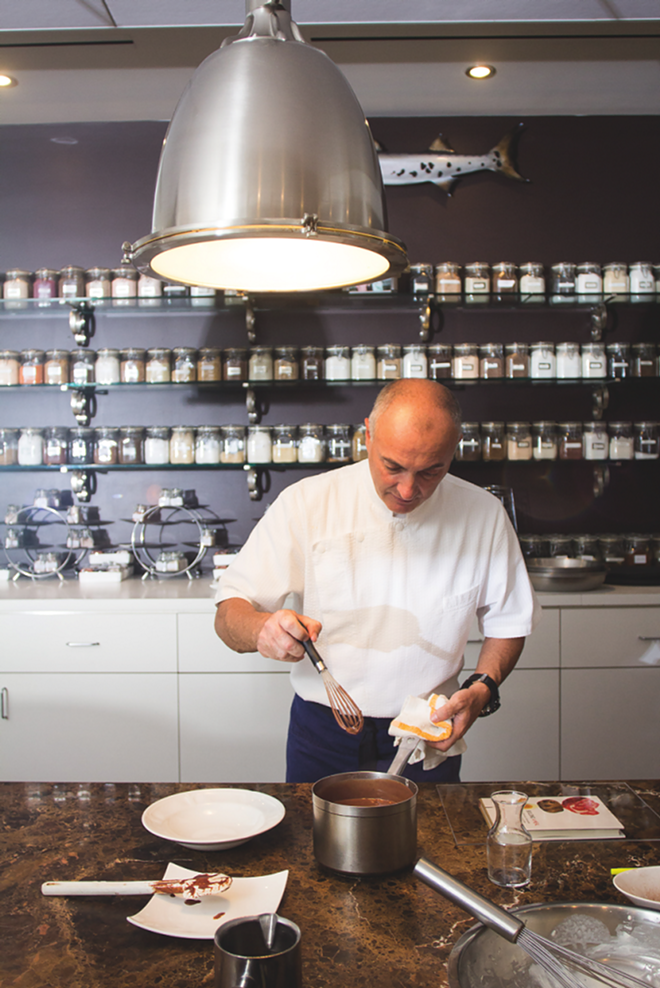 Fabrizio Aielli cooking at Sea Salt No. 1, with a wall of jarred salts from locales like El Salvador and Bali behind him. - Sea Salt