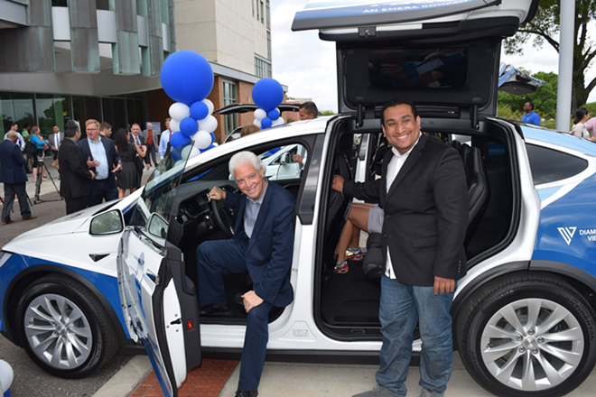 Tampa City Councilman Mike Suarez and Roberto Torres, owner of the Blind Tiger Cafe, pose with the Tesla Model X that will be used for HyperLINK services.