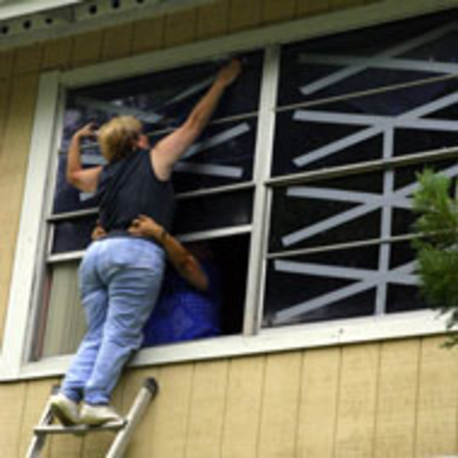 HANDS ON: Veronica Gilbert, with aid from her - mother, tapes windows on her home in Tampa. - GWENDOLYN RODRIGUEZ