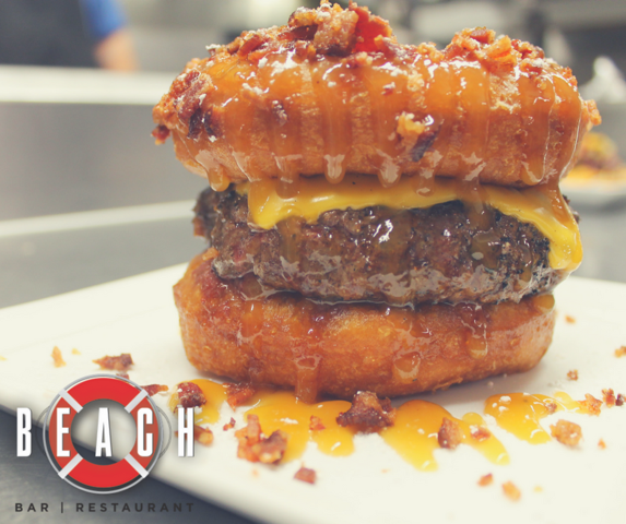 Beach's doughnut burger, with a beignet-style bun, American cheese, bacon and caramel sauce. - Beach Bar & Restaurant