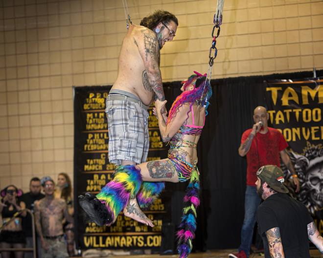 SWINGIN' TIME: Season 5 Ink Master competitor Robbie Ripoll  is suspended above the stage at the  Tampa Tattoo Convention. - CHIP WEINER