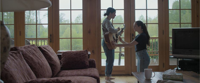 Anna (Mina Walker, left) and Beth (Joan Glackin) learn to play guitar in the chilling medical horror thriller, "Silence & Darkness" - Alarm Pictures