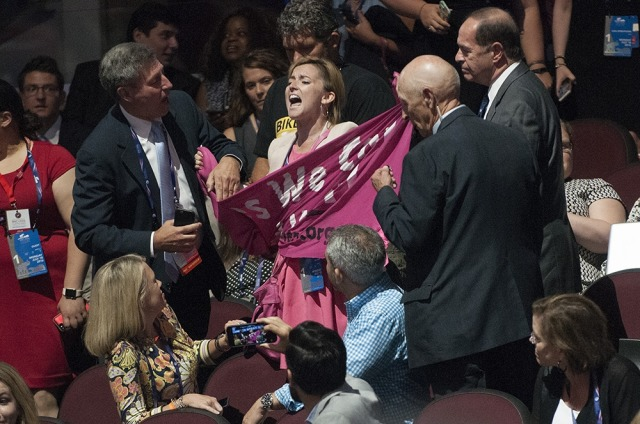 A Code Pink protester inside the arena struggles to unfurl her banner. - Joeff Davis