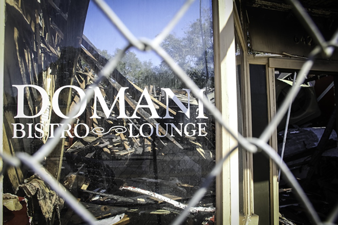 REFLECTIONS OF DEVASTATION: A fire-damaged collapsed roof can be seen through Domani's front window. - DANIEL VEINTIMILLA