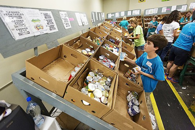 A volunteer sorts canned goods at Feeding America's Tampa warehouse - Chip Weiner