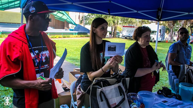 Volunteers hand out information Tuesday in Williams Park. - daniel veintimilla