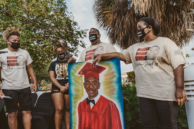 Andrew Joseph III's family stands with a painting of their late loved one. - Yvonne Gougelet