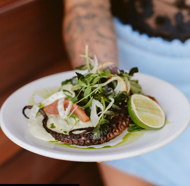 Accents of charred scallion crema on Wild Child's jerk octopus are plated with wafer-thin circles of fennel, small peeled grapefruit segments, red watercress leaves, sliced rings of pickled sweet peppers, and a spritz of fresh lime juice meld beautifully on the plate. - Kristina Holman via Wild Child