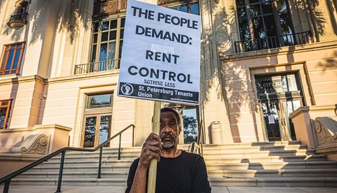 A protester at St. Petersburg City Hall holds a sign demanding rent control. - Photo by Dave Decker