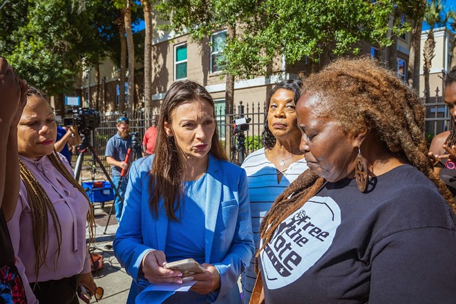 Nikki Fried (center) speaking with Connie Burton (right) and other community members outside Tampa's Silver Oaks apartments on April 19, 2022. - Dave Decker