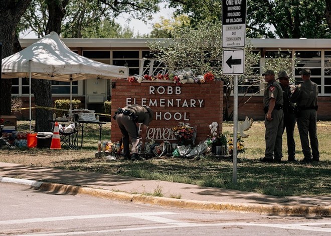 Members of law enforcement lay flowers at a makeshift memorial outside Robb Elementary School. - Photo by Joseph Guillen