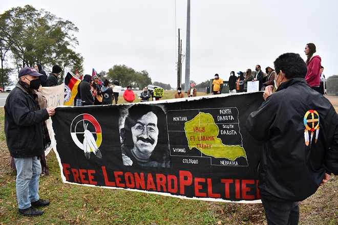 Activists hold a banner calling for Leonard Peltier's release outside of Coleman Penitentiary in Florida. - PHOTO BY JUSTIN GARCIA