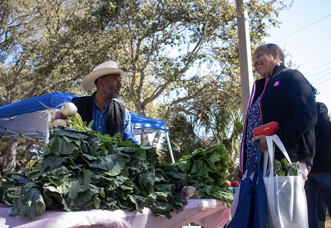 Ocala farmer Howard Gunn sells collard greens to a festival attendee. - Angelique Herring