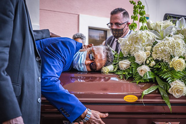 Kent Racker (center) hugs the casket holding his brother Gregory Jacobs, aka Shock G, as MC Serch (background) and Too Fly Eli (hand) offer support.