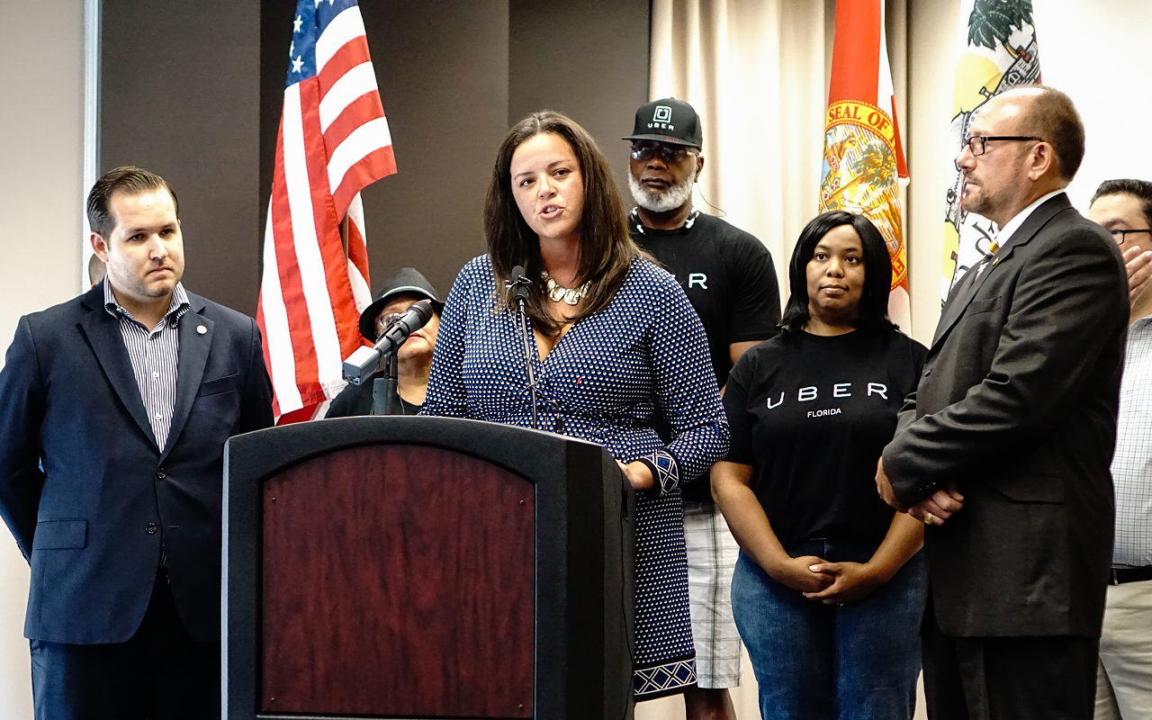 Uber spokesperson Stephanie Smith (center) speaks at a press conference about the temporary operating agreement reached with Public Transportation Commission Chair Victor Crist (front right).