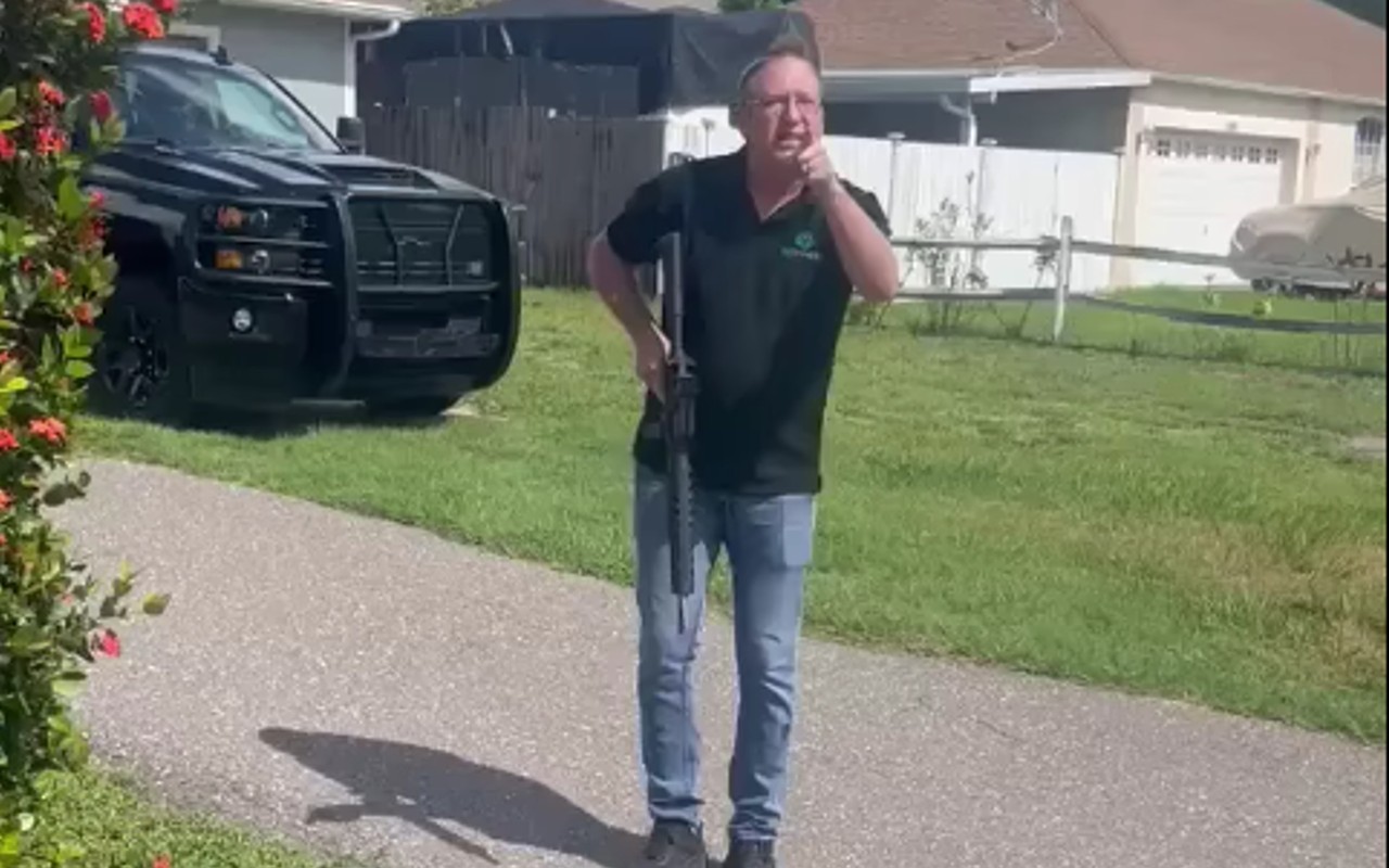 Screenshot from a video showing David H. Berry holding a gun while pointing and shouting at landscapers.